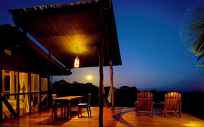 An outdoor wooden deck with a covered seating area, a hammock, and a view of the night sky. - Casa Vikingo • A Unique, Secluded Highland Cabin (bellavista)