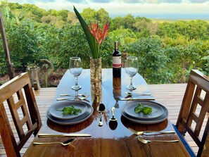 A wooden table set for two with wine glasses, a bottle of wine, and plates with green leaves. - Casa Vikingo • A Unique, Secluded Highland Cabin (bellavista)
