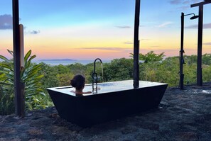 Eine Badewanne in idyllischer Umgebung mit Blick auf den Himmel und grüne Natur.
