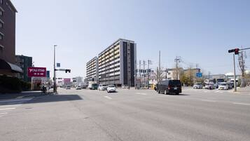 A multi-story building with a modern design, located at a busy intersection with traffic lights and various vehicles.