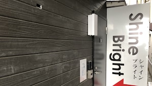Entrada de hotel con un cartel que dice "Shine Bright" y una flecha indicadora.