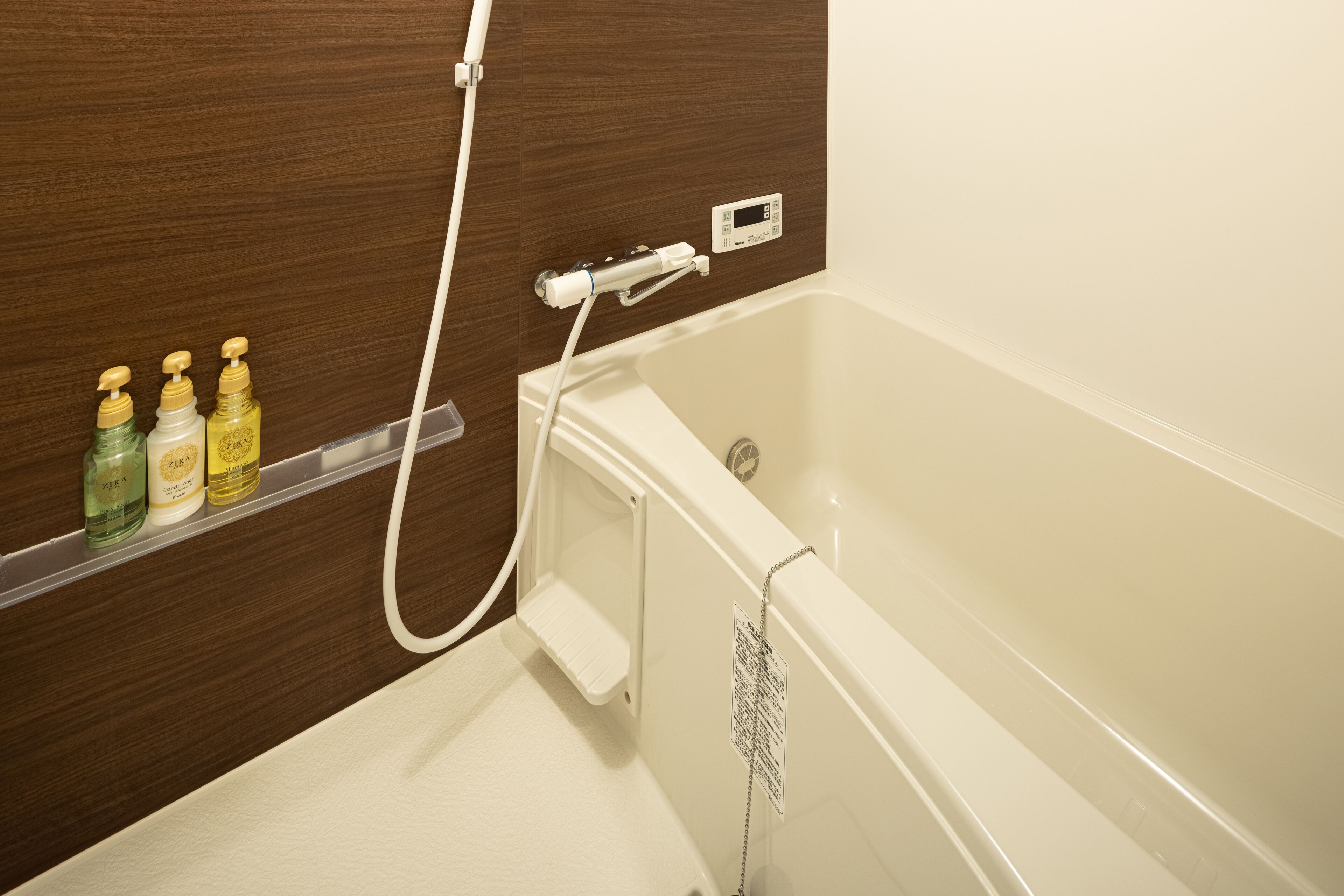 A bathroom with a bathtub, a shower, and a shelf with toiletries.