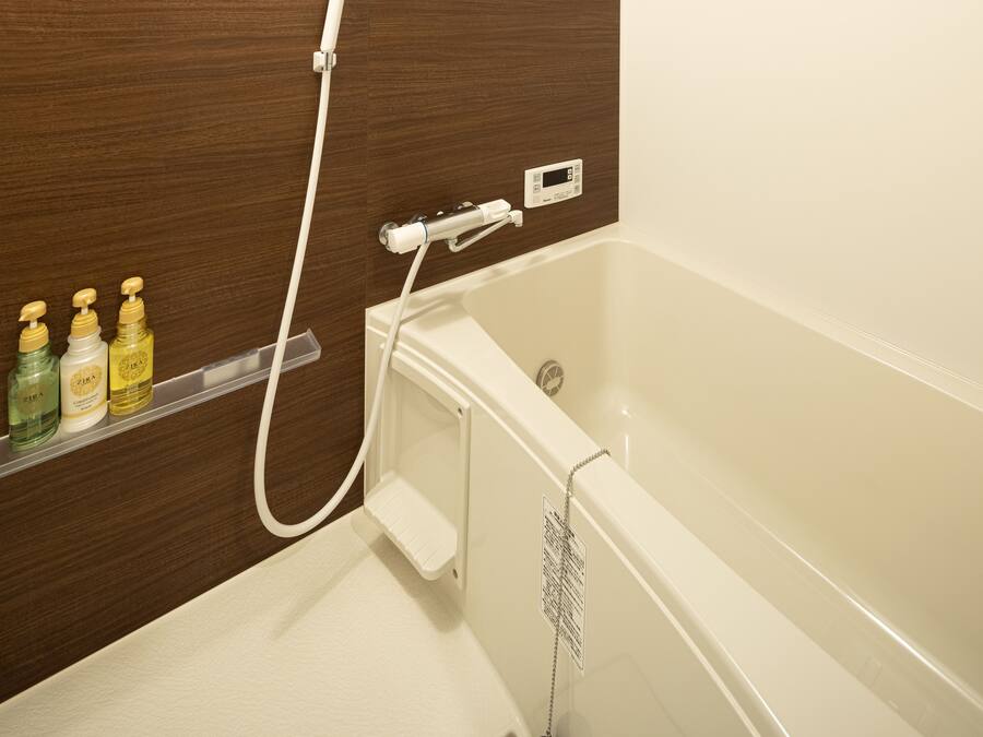 A bathroom with a bathtub, a shower, and a shelf with toiletries.