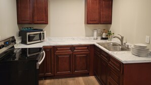 Una cocina con armarios de madera, un lavamanos de acero inoxidable, un microondas y una estufa.