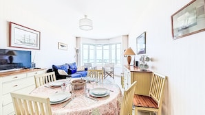A dining area with a round table, chairs, and a TV on a stand. - Les Armateurs by Interhome (Saint Malo)