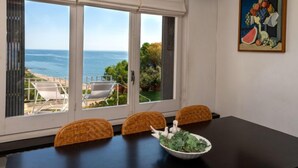 Un comedor con vistas al mar, una mesa con sillas y un cuadro en la pared.