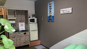 A compact room with a kitchenette, a bed, and a wall-mounted sign. - Guest House Zen Hakata (Fukuoka)