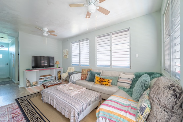 A living room with a sofa, a TV, and a ceiling fan.