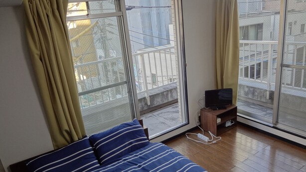 Ein Schlafzimmer mit einem Bett, einem Fernseher auf einem Schrank und einem Fenster mit Vorhängen.