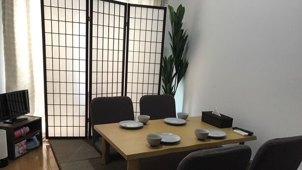 Een eetgedeelte met een tafel voor vier personen, stoelen, een televisie en een plant.