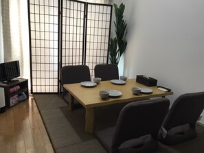 Een eetgedeelte met een tafel voor vier personen, stoelen, een televisie en een plant.