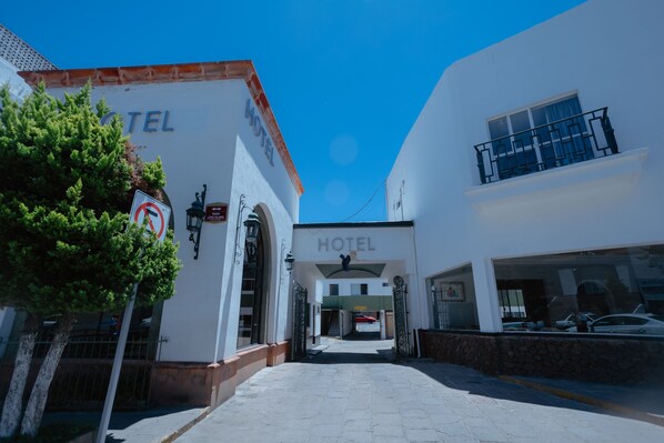 A hotel entrance with a clear pathway leading to the main doors, a no parking sign, and a tree on the left. - Hotel Zacatecas Courts (Zacatecas)