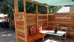 A wooden bench with a cushioned seat and backrest, a small table, and a potted plant. - Small studio in the quite neighbourhood. (Flagstaff)