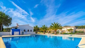 Una piscina azul cristalina con un edificio blanco y palmeras al fondo.