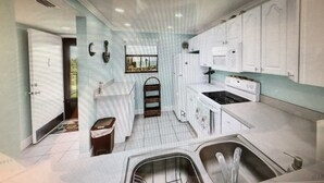 A modern kitchen with white cabinets, a stove, and a sink. - Condo with 2 bedrooms (Jensen Beach)
