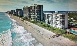 A beachfront hotel with multiple high-rise buildings, a sandy beach, and a pool area.