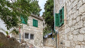 A narrow stone pathway leading to a building with green shutters and a metal bench. - Apartment Historic Split - Bova (Split)