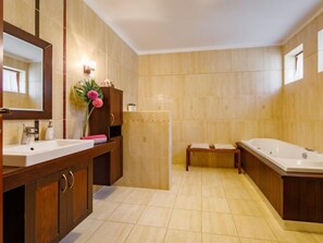 A modern bathroom with two sinks, a large mirror, a wooden vanity, and a bathtub.