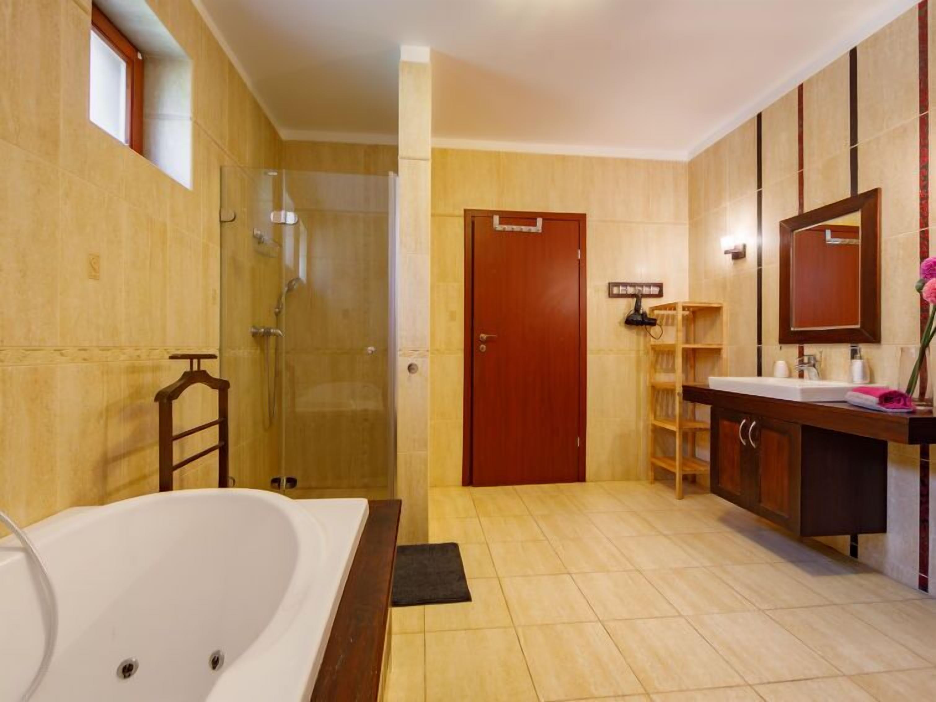 Ein modernes Badezimmer mit einer großen Badewanne, einer Duschkabine und einem Holzbadezimmermöbel mit Spiegel.