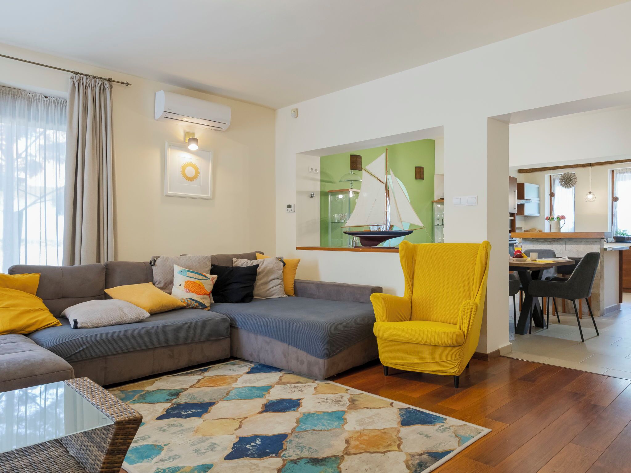 A living room with a sofa, armchair, and a colorful rug.