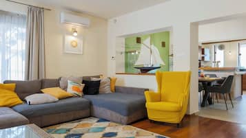 A living room with a sofa, armchair, and a colorful rug.