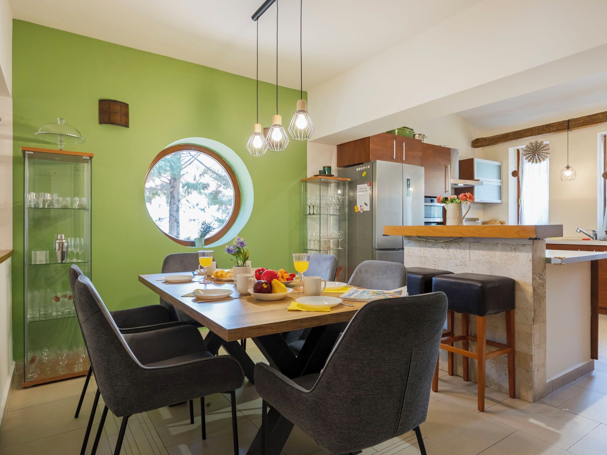 Une cuisine moderne avec un coin repas, des murs verts et une grande fenêtre.