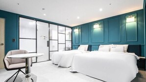 A hotel room with two beds, a white table, and a chair. - Hotel Luna (Hwaseong)