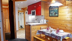 A cozy kitchen with wooden cabinets, a dining area with a table set for two, and a small island with a microwave.