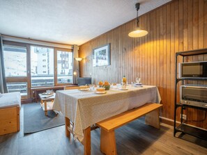 Una habitación acogedora con paredes de madera, una mesa de comedor con lo necesario para el desayuno, un banco y una kitchenette con microondas.
