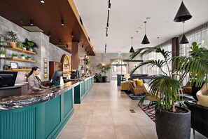 Een hotel receptie met een balie, receptiepersoneel en een zithoek.