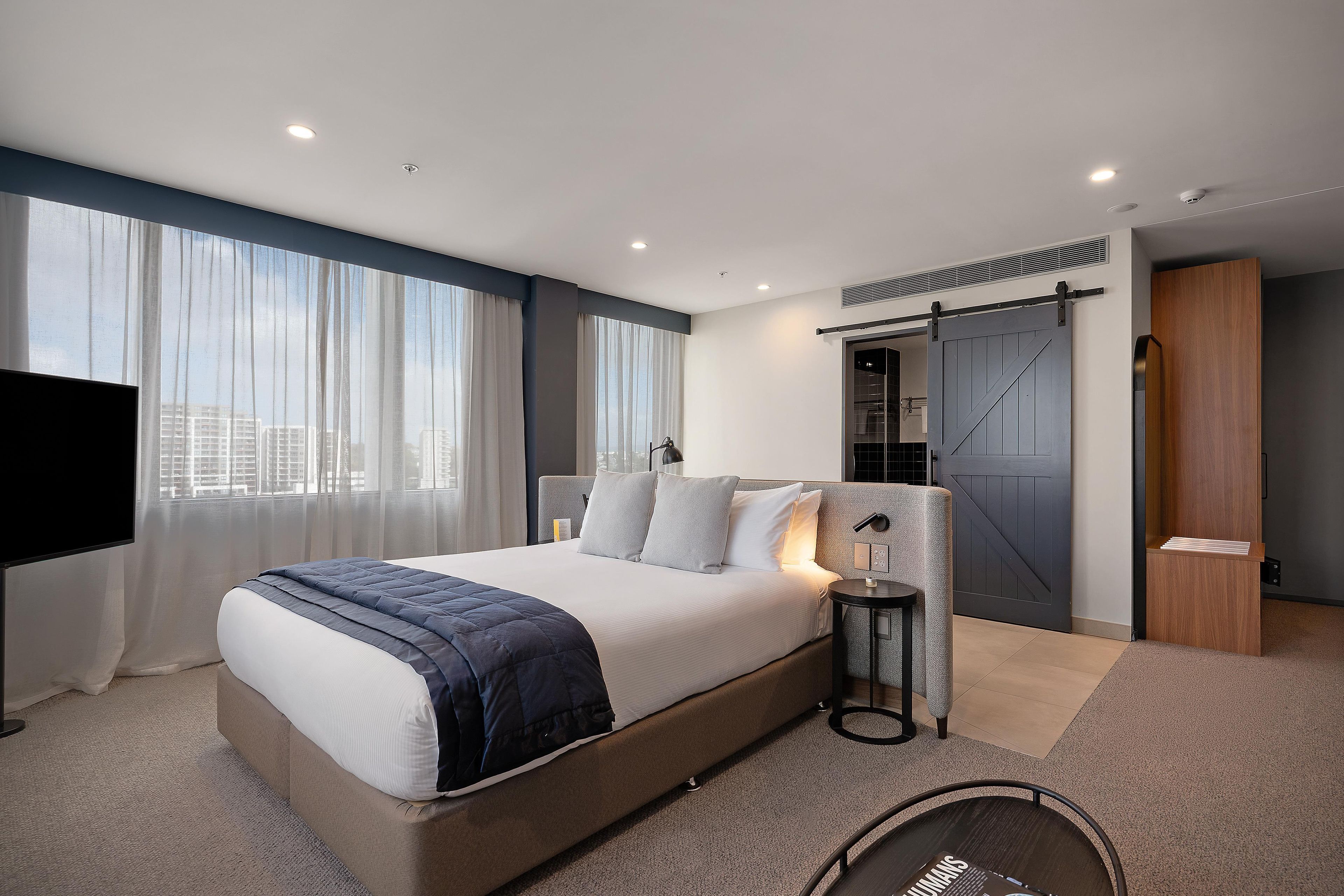 Une chambre d’hôtel moderne équipée d’un grand lit, d’une télévision, d’un bureau et d’une porte coulissante.