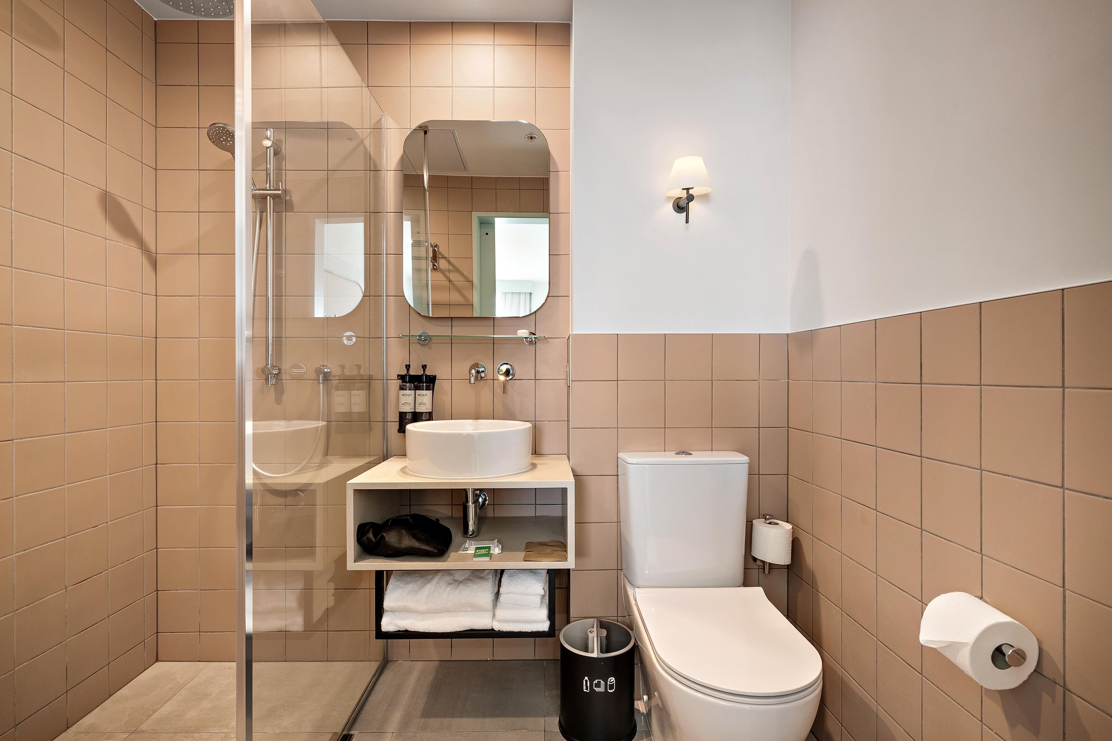 A modern bathroom with a glass-enclosed shower, a sink, a toilet, and a mirror.