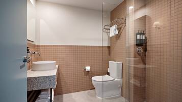 Une salle de bain moderne avec une douche à parois de verre, un lavabo blanc et des toilettes.