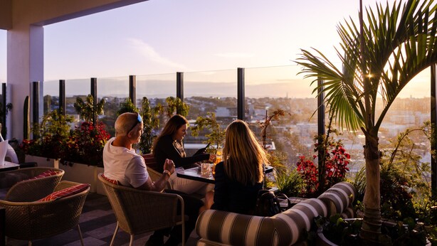 A terrace with wicker furniture, potted plants, and a view of the cityscape. - Sudima Auckland City (Auckland)