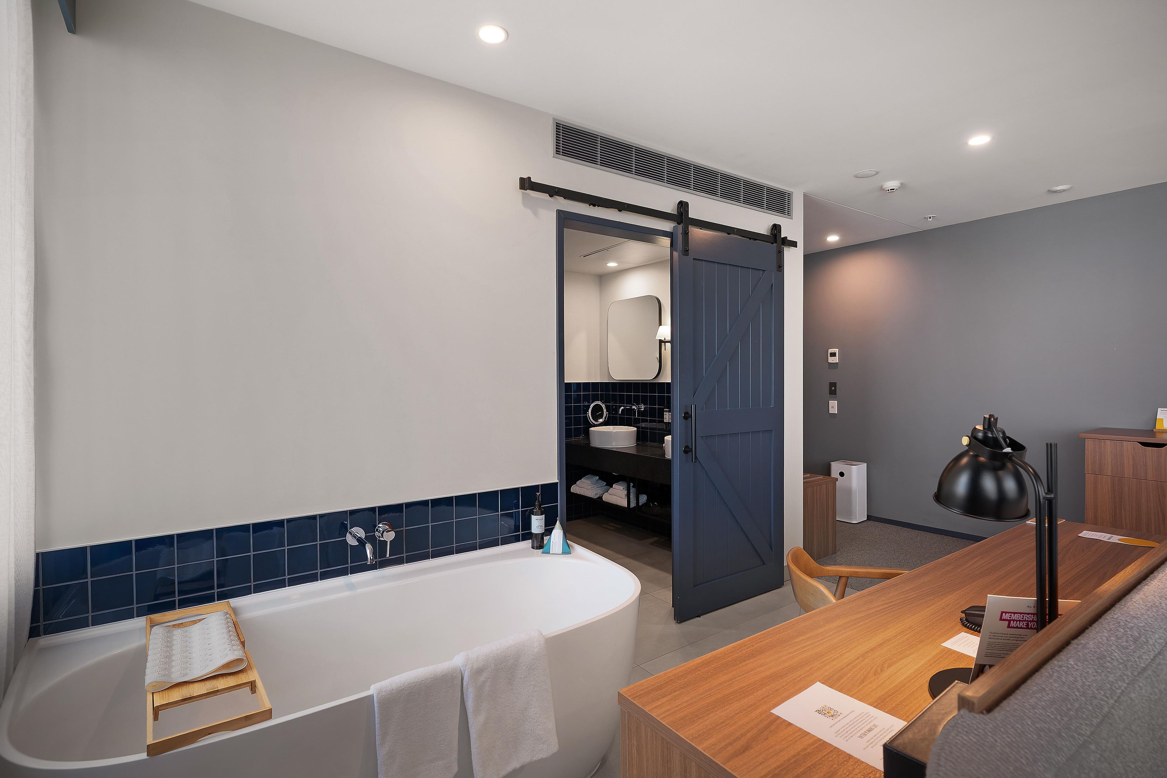 Een moderne badkamer met een vrijstaand bad, een houten wastafelmeubel en een grote spiegel.