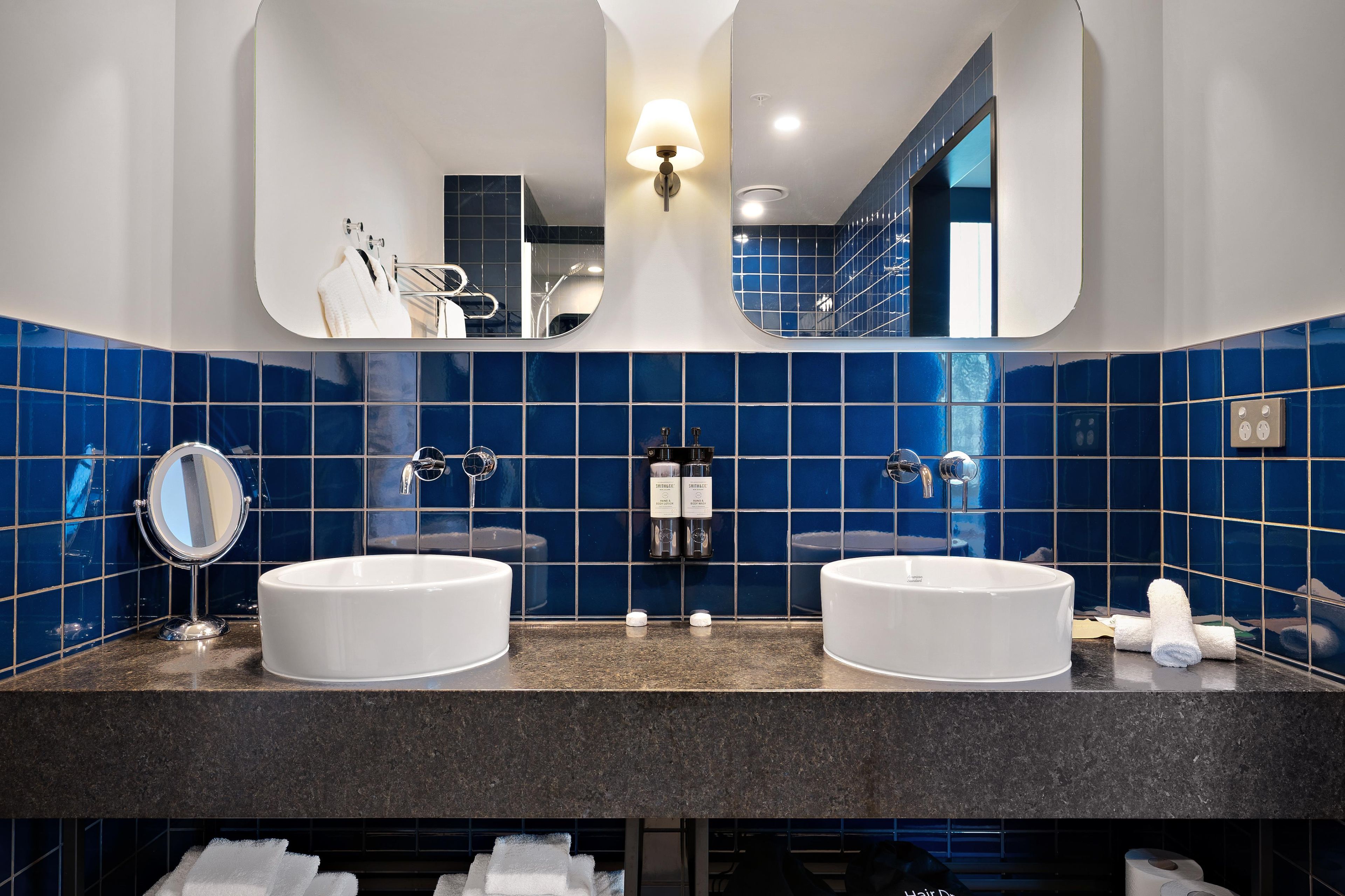 A bathroom with two sinks, a mirror, and a towel rack.