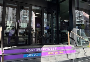 A fitness center entrance with glass doors, a sign for a free 7-day trial, and a 24/7 open sign. - Sudima Auckland City (Auckland)