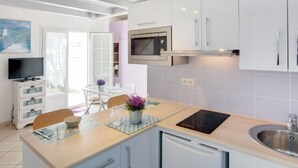 Uma cozinha moderna com armários brancos, micro-ondas embutido e uma pia de aço inoxidável.