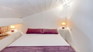 Quarto com uma cama grande, duas luminárias de cabeceira e uma mesa de cabeceira com abajur.