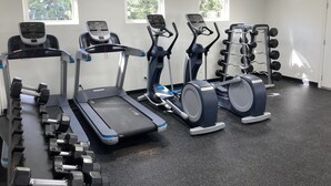 Une salle de sport équipée de tapis de course, de vélos elliptiques et d’un banc de musculation.