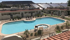 Une piscine avec un jacuzzi, entourée d’une clôture, et des panneaux solaires installés sur les toits.