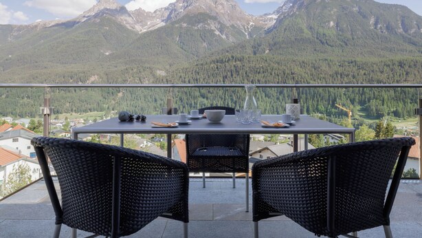 Un balcón con una mesa para dos, con vistas a un paisaje montañoso.