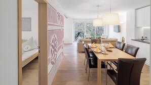 Un comedor moderno con una mesa de madera, sillas negras y un sofá al fondo.