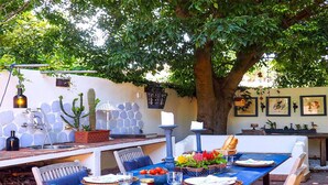 An outdoor dining area with a blue table, chairs, and a variety of plants and decorations. - Mondello Villa the two palm trees (Palermo)