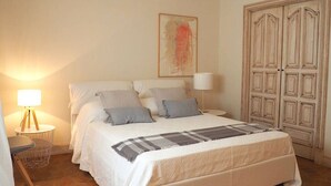 A bedroom with a large bed, two bedside tables, a lamp, and a wardrobe. - Mondello Villa the two palm trees (Palermo)