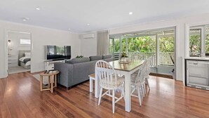 Een moderne woonkamer met een bank, televisie, eettafel en stoelen.