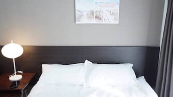 A hotel room with a neatly made bed, a bedside table with a lamp, and a wall-mounted picture.