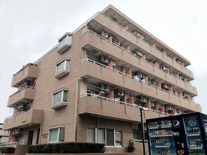 En flervåningsbyggnad med bostäder, balkonger, en försäljningsautomat och en väl synlig skylt.