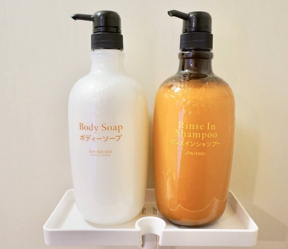 Two bottles of body soap and rinse-in shampoo on a white tray.