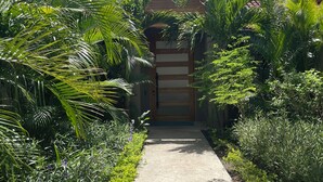 A pathway leading to a building with a tiled roof and a wooden door.